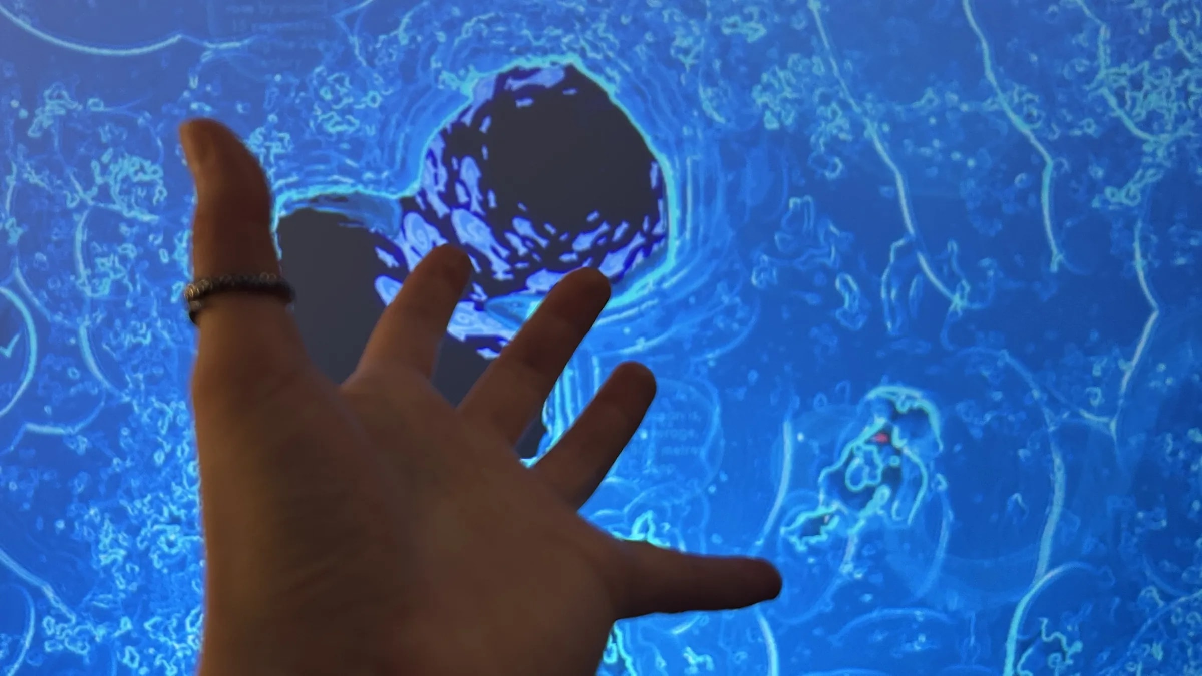 Besucher interagiert mit der Installation „Bend the Water“ und verändert eine digitale Wasserprojektion mithilfe von Handtracking in Echtzeit.
