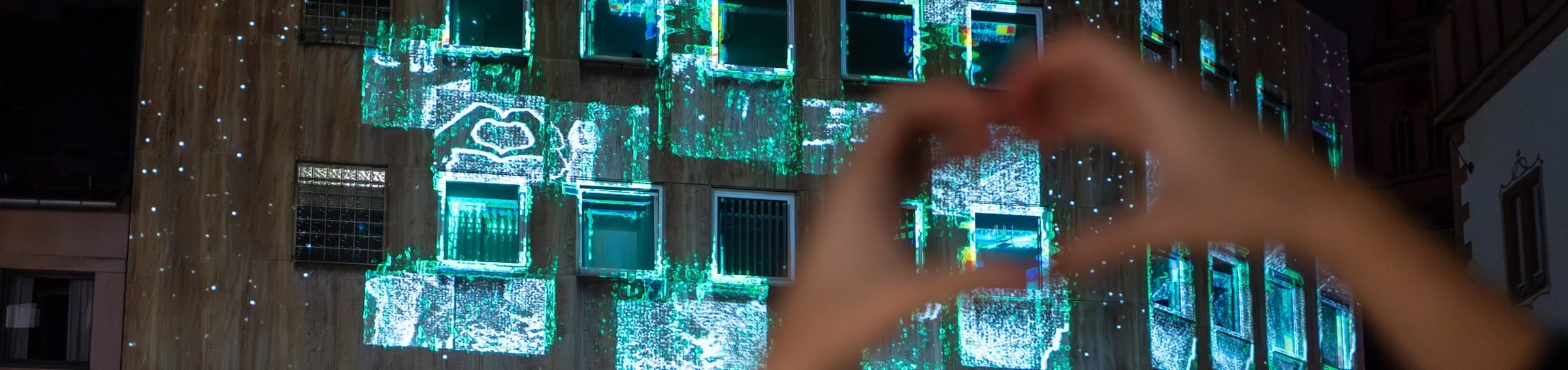 Interaktive Fassadenprojektion Echoes 2.0 in Türkis und Grün auf einer Hausfassade beim Festival Mainz Leuchtet