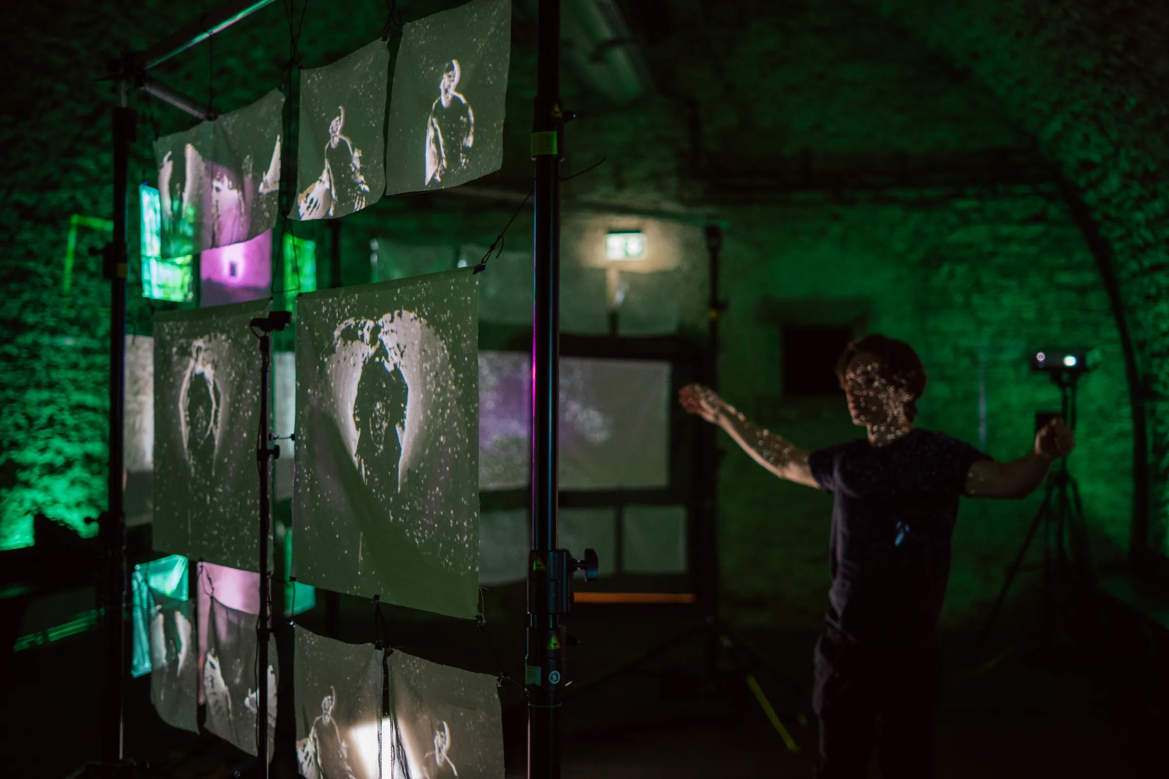 Besucher steht mit ausgebreiteten Armen vor den Projektionsflächen der Installation Echoes from Beyond in der Kulturei Mainz