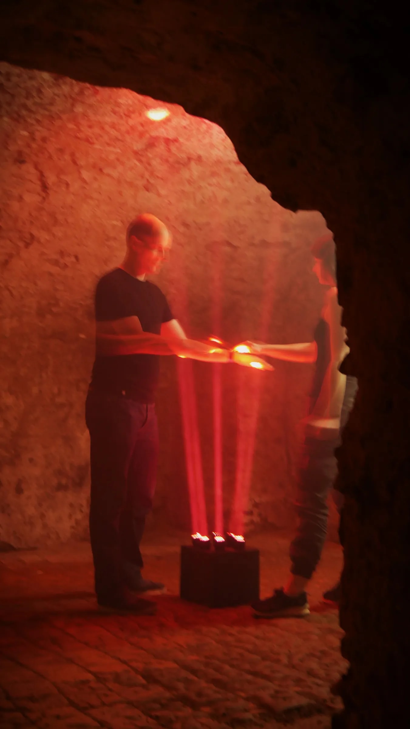 Besucher greift mit beiden Armen in die roten Lichtstrahlen der Installation Play the Light im Gewölbe Oppenheim