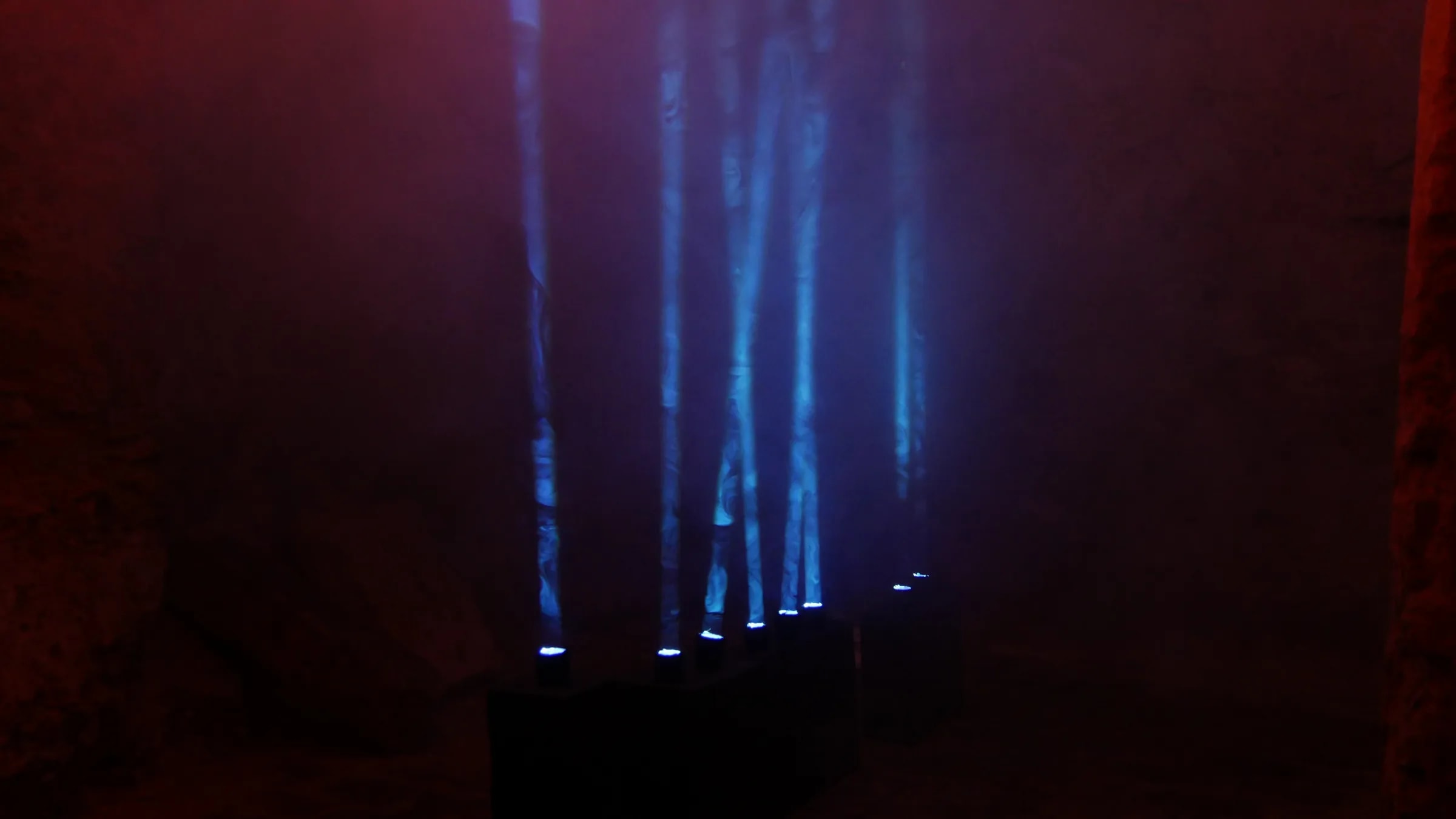 Blaue Lichtstrahlen der Installation Play the Light stehen senkrecht im Nebel des Kellerlabyrinths Oppenheim