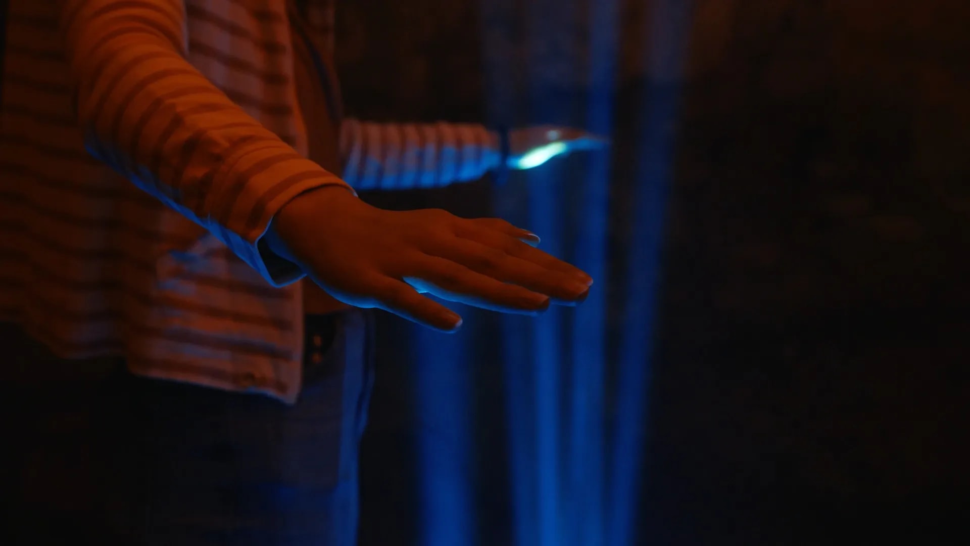 Hand im blauen Lichtstrahl der Installation Play the Light im Synthesizer-Modus
