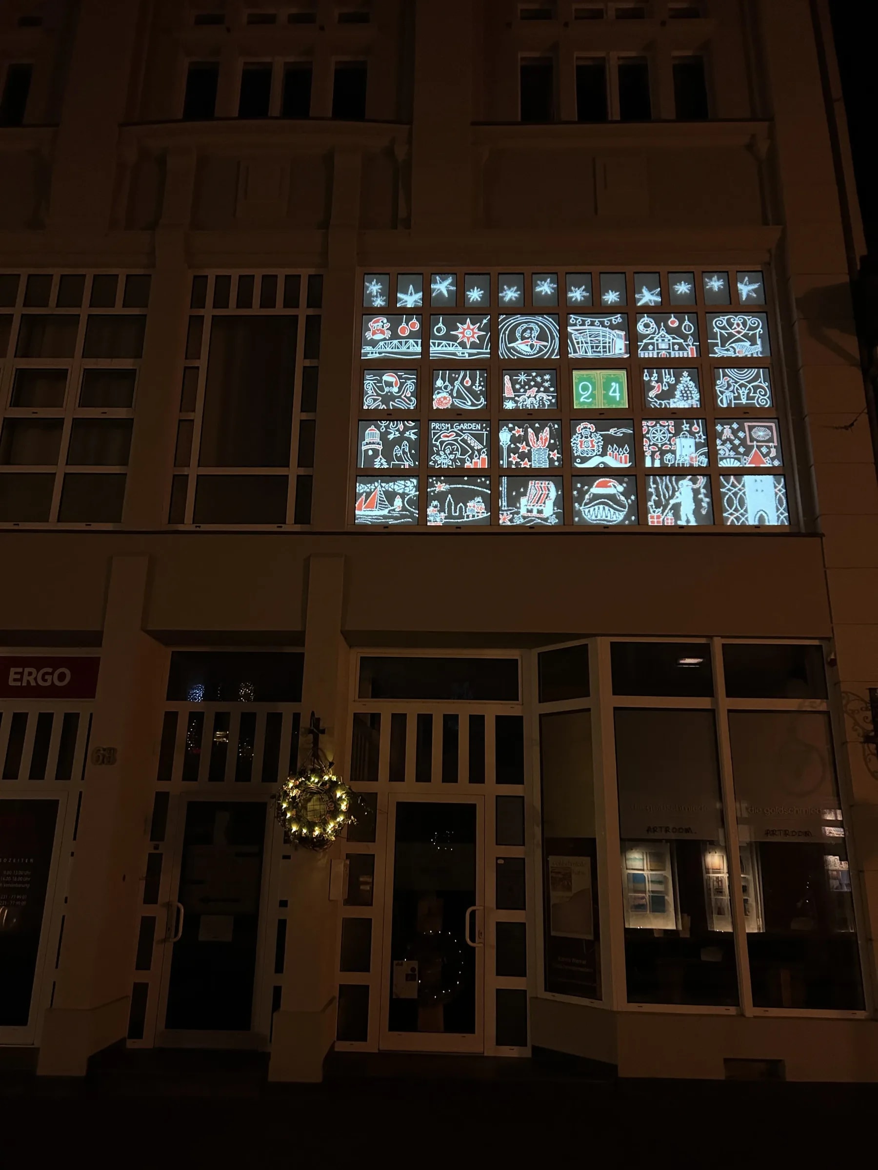Projected advent calendar on the window front of a period building in Barth: 23 opened doors with Christmas and Baltic Sea motifs, only green door 24 still closed.
