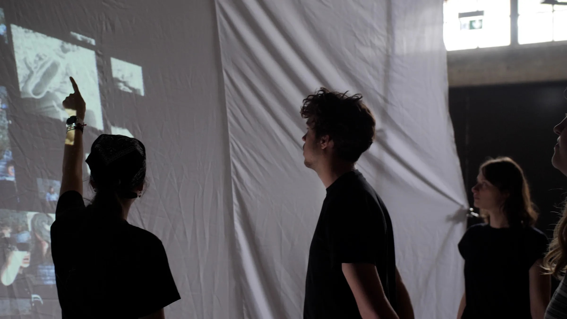 Besuchende erkunden gemeinsam die Projektionswand der interaktiven Medieninstallation „Echoes from Beyond“.