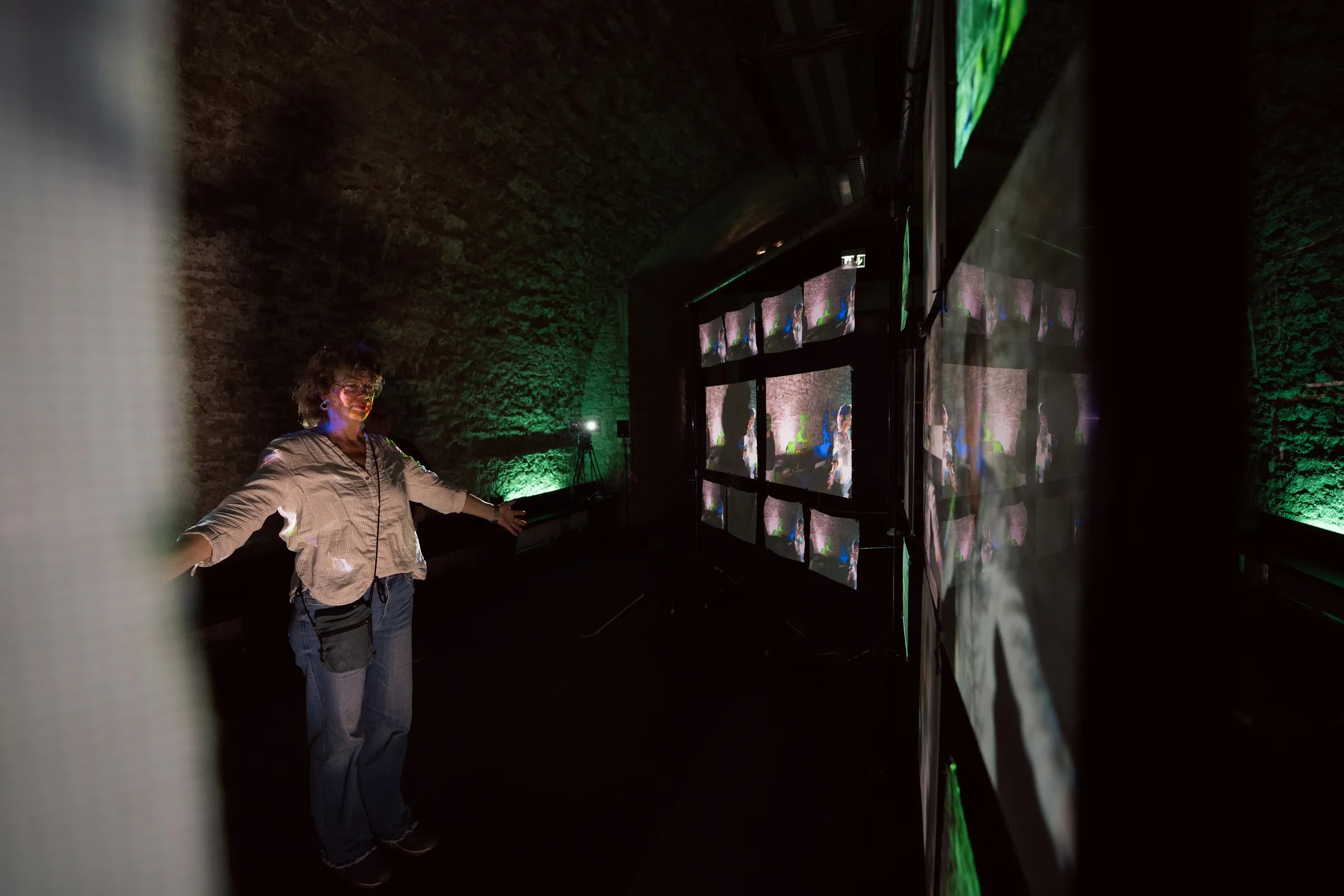 Eine Besucherin interagiert mit den Projektionsflächen der interaktiven Rauminstallation „Echoes from Beyond“ in der Kulturei Mainz.