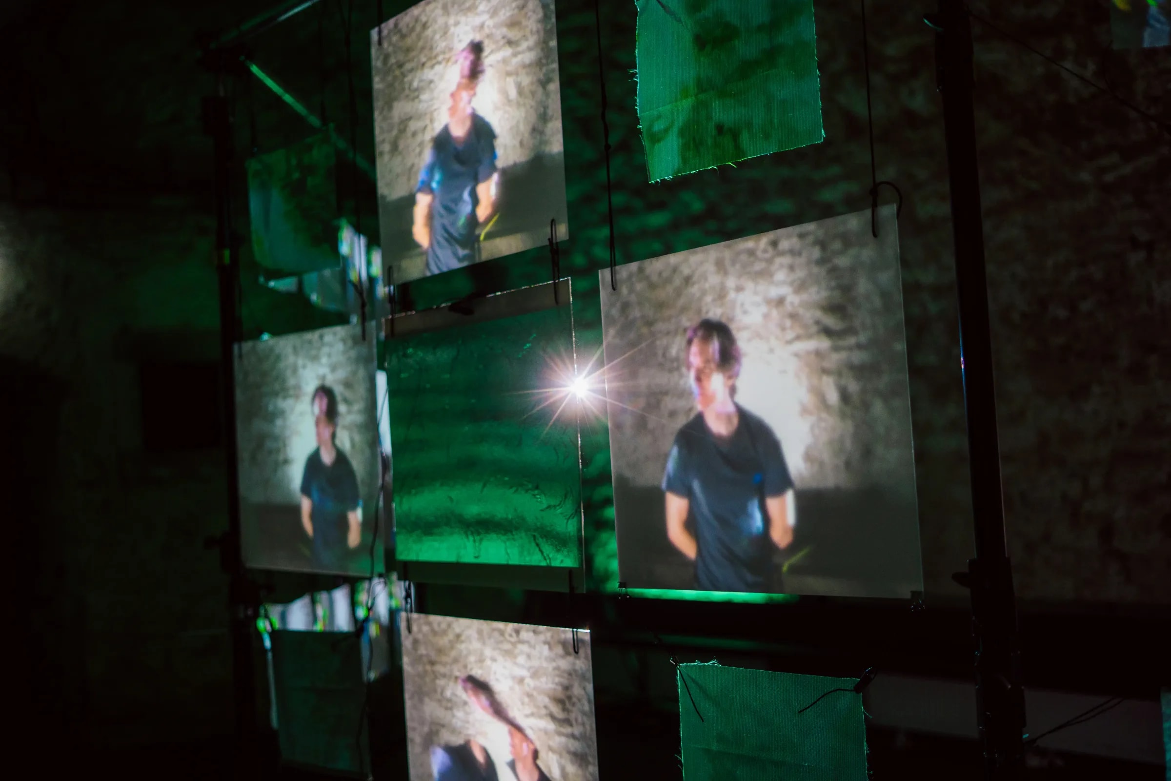 Mehrere Projektionsflächen zeigen das Echtzeit-Abbild einer Person innerhalb der interaktiven Installation „Echoes from Beyond“.